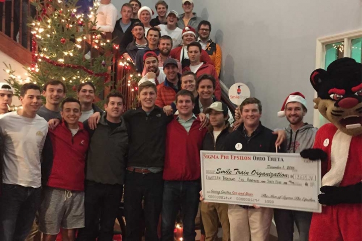 Large group pose with Smile Train donation check with school mascot