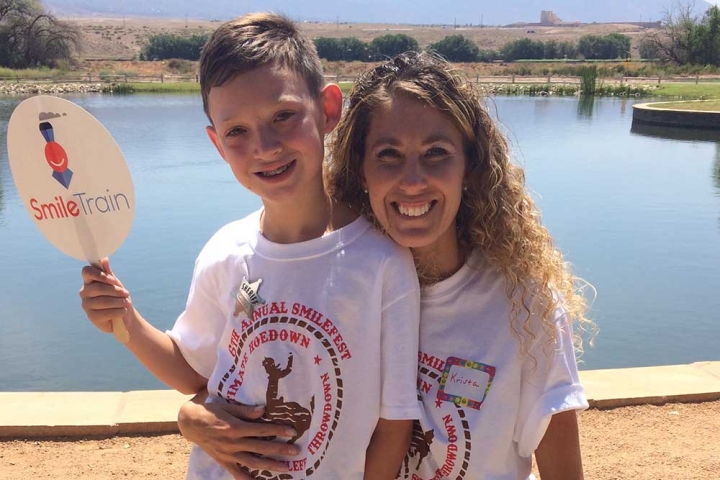 Krysta with her son holding a Smile Train sign