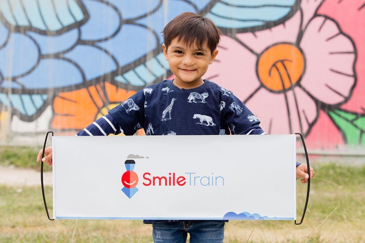 Boy holds up a Smile Train pull out banner