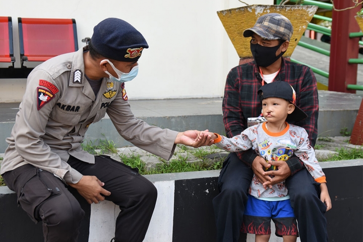 Indonesian police officer reaches out to a child with a cleft before his free Smile Train surgery.