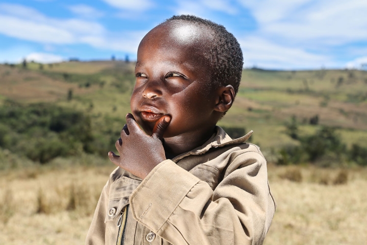 Benjamin thinking in a field in Kenya after his Smile Train-sponsored cleft surgery