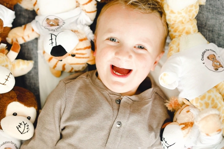 Krista's son surrounded by Cuddles for Clefts stuffed animals with clefts