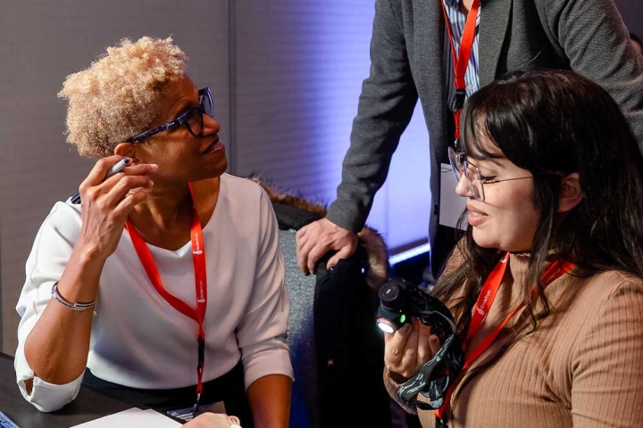 r. Judy Ward and another doctor sitting down with a Simulare cleft model on the table. They are talking to Dr. Juan Carlos Zambrano who is standing over them and leaning on their chairs.