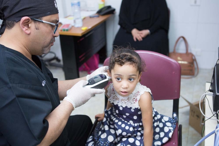 Smile Train partner using hearing monitor on a cleft-affected patient