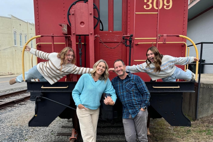 Hough family holding hands standing in front of a train