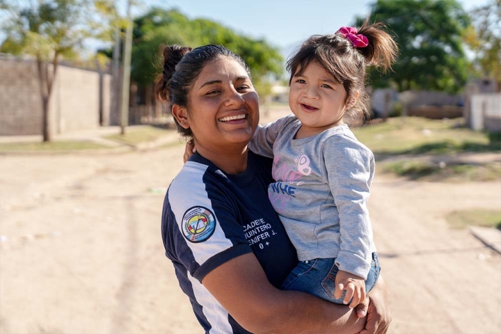 A smiling Jenifer holds Isabella in her arms