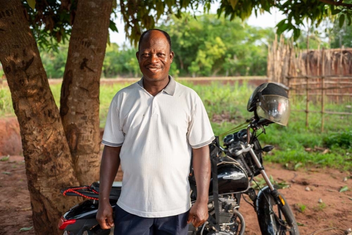 Koli stands in front of his motorcycle and smiles