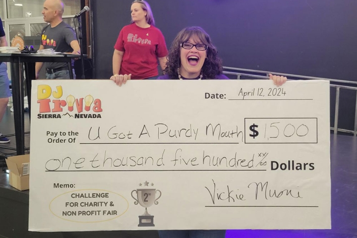 Jamie Hawkins holding a big $1,500 check for her team’s trivia winnings