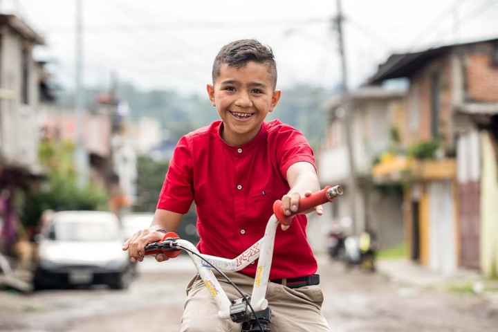 Jesus smiling and riding his bike after cleft surgery