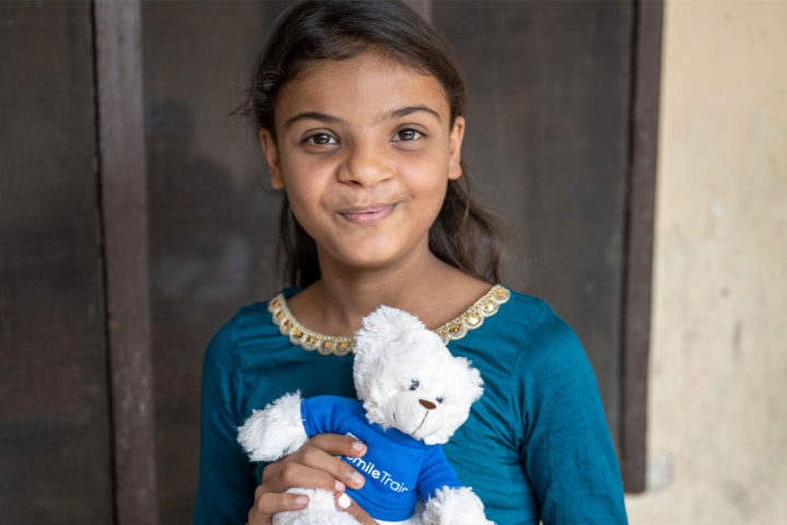 Paulwin smiling and holding a Smile Train teddy bear after cleft surgery