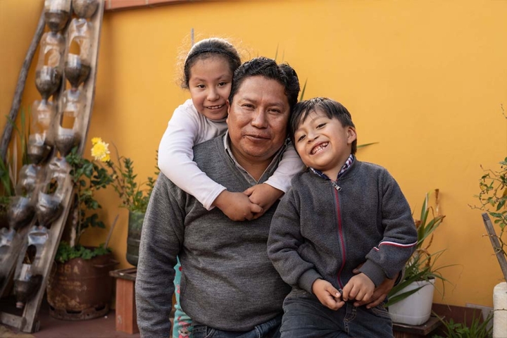 Rene smiles with his daughter, Anahí, and his son, Daniel. Anahí stands behind him and wraps her arms around him. Daniel smiles and nestles against his shoulder