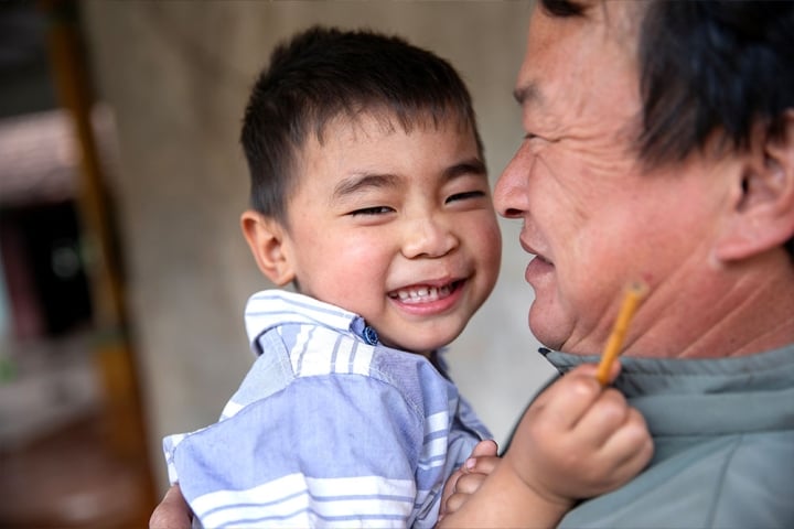 Gau grins as his grandpa holds him affectionately in his arms