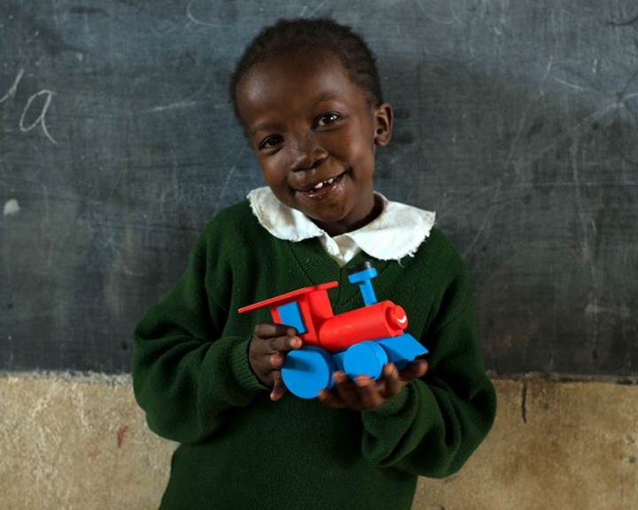 Girl holds a train in front of chalkboard