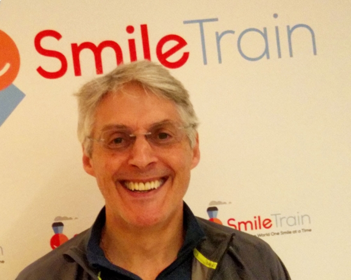 Geoff poses in front of Smile Train backdrop