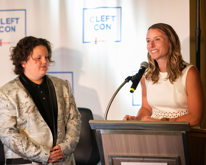 Allie Bowels speaks at Cleft Con, with Conrad by her side