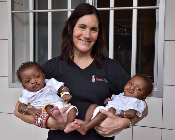 Susie carrying two baby Smile Train patients