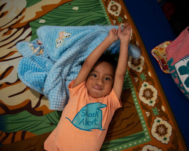 Anghelo laying face-up on a blanket, stretched out.