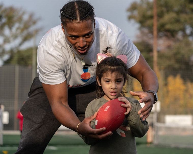 Kenyan shows a football clinic participant how to hold the ball