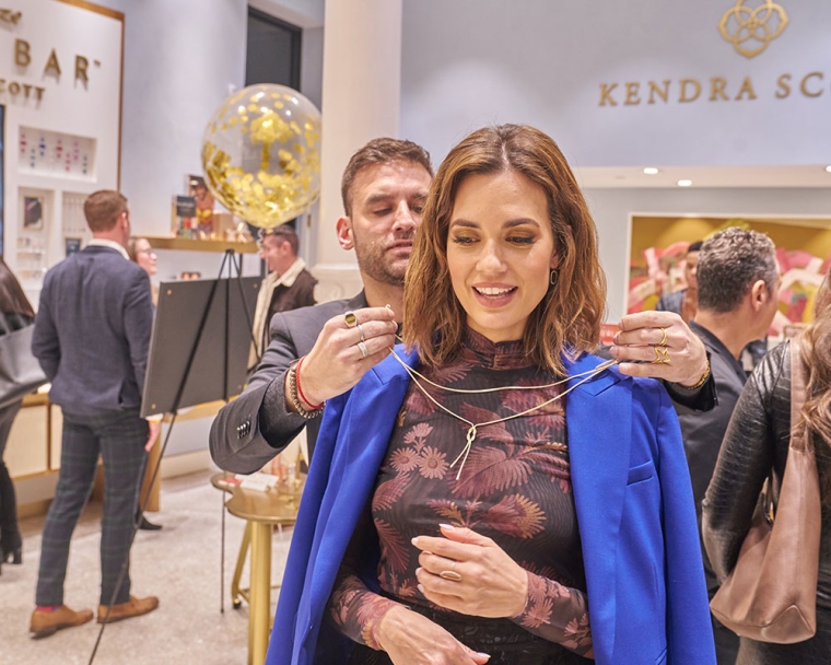 Torrey DeVitto trying on a necklace at the Kendra Scott Giving Tuesday event