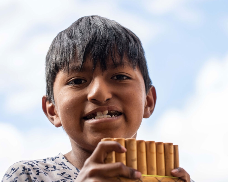 Luis smiling and playing the pan flute