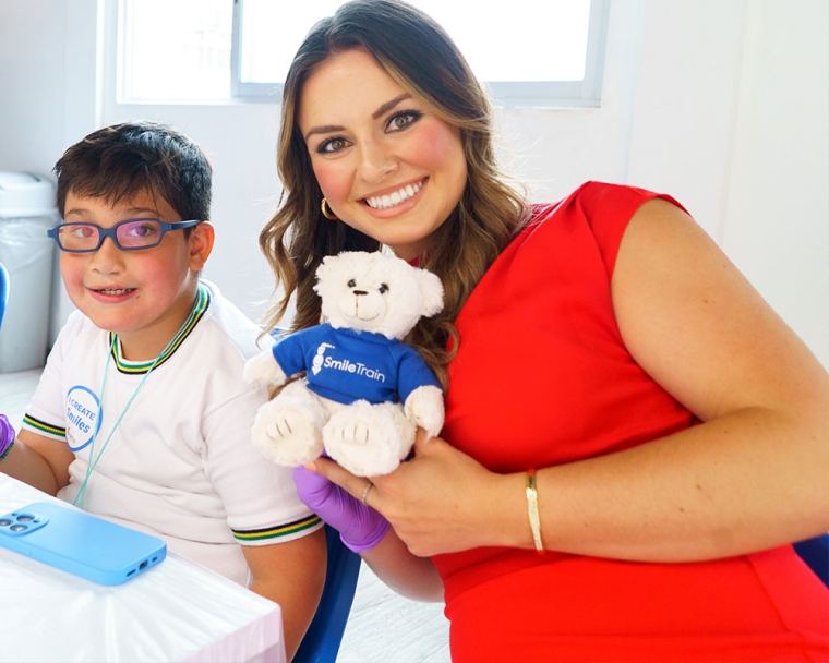 Tammy holding a teddy bear and smiling with a patient