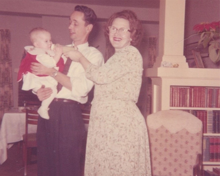 Linda's parents smiling and feeding her as a baby