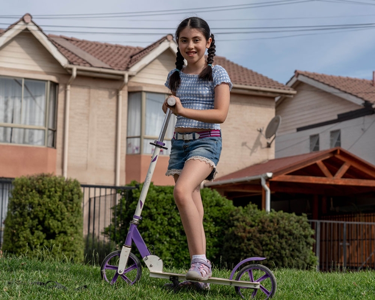 Amelie smiling and riding a scooter after cleft surgery