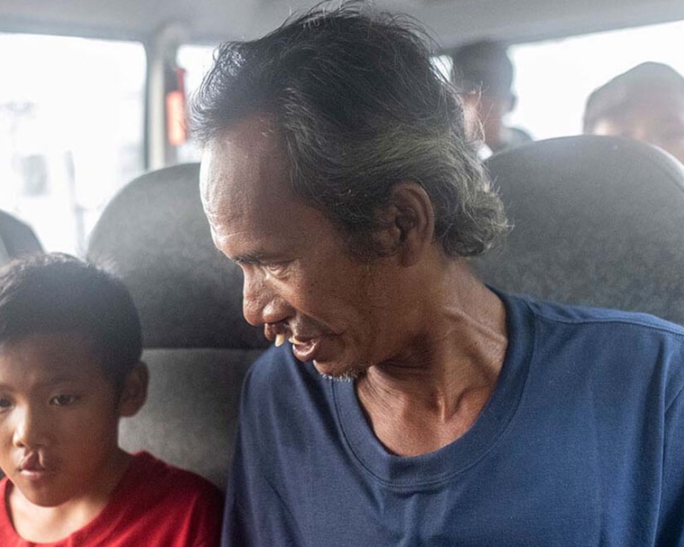 Alim smiling and sitting next to Rajib in a van