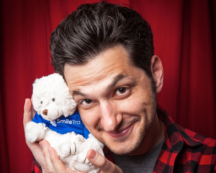Ben Schwartz smiling with a Smile Train teddy bear