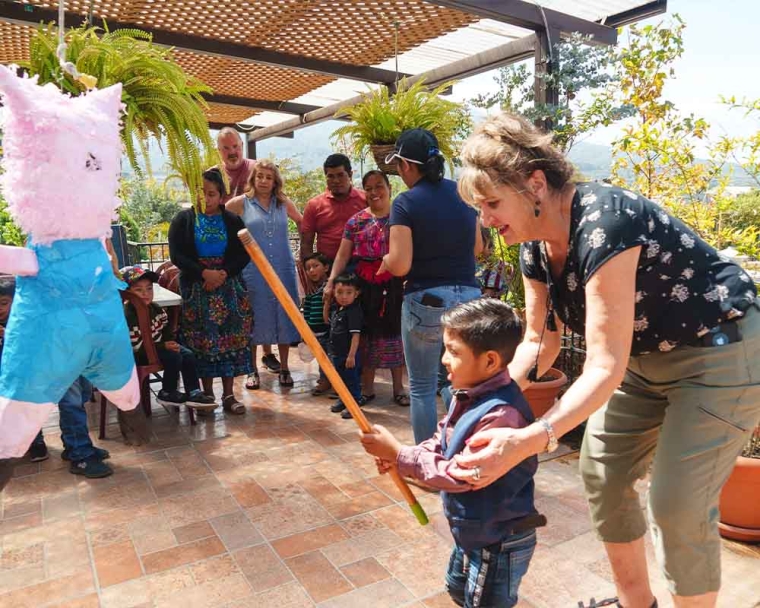 Sue Hoover helping a Smile Train patient break a piñata in Guatemala