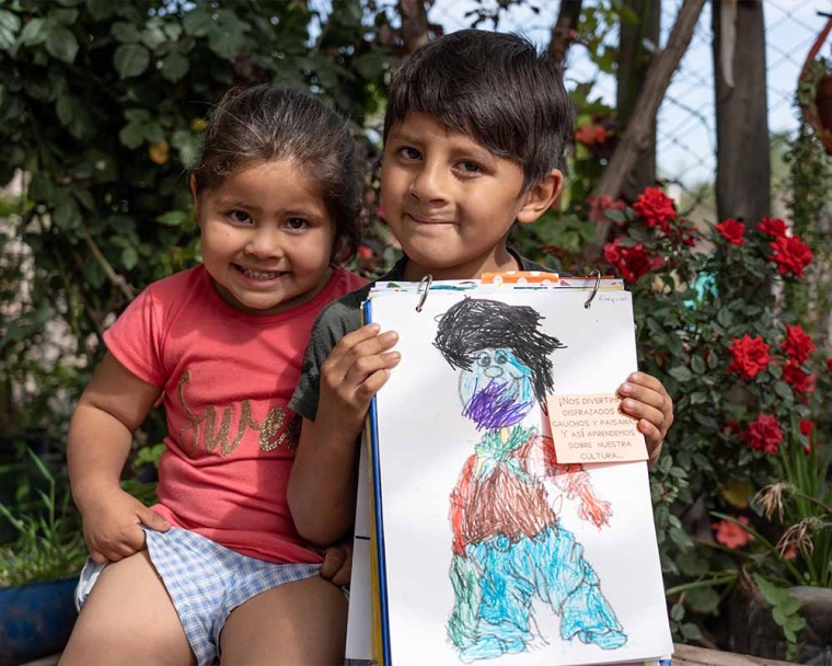 Ezequiel smiling and holding a drawing with his sister after cleft surgery