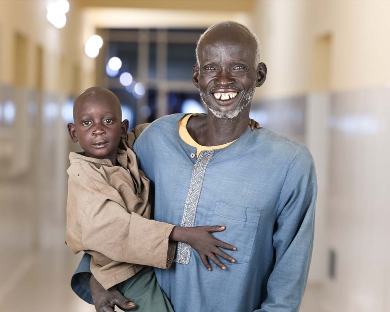 Machiek Majok smiling and hugging his father Nhomngeng