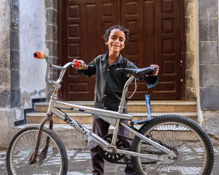 Bilal smiling and holding his bike after cleft surgery