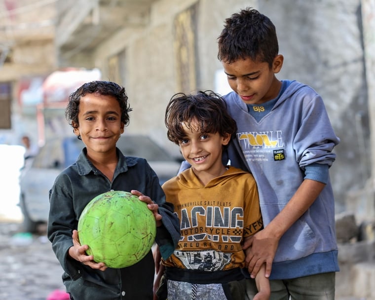 Bilal smiling with his brothers and holding a soccer ball after cleft surgery