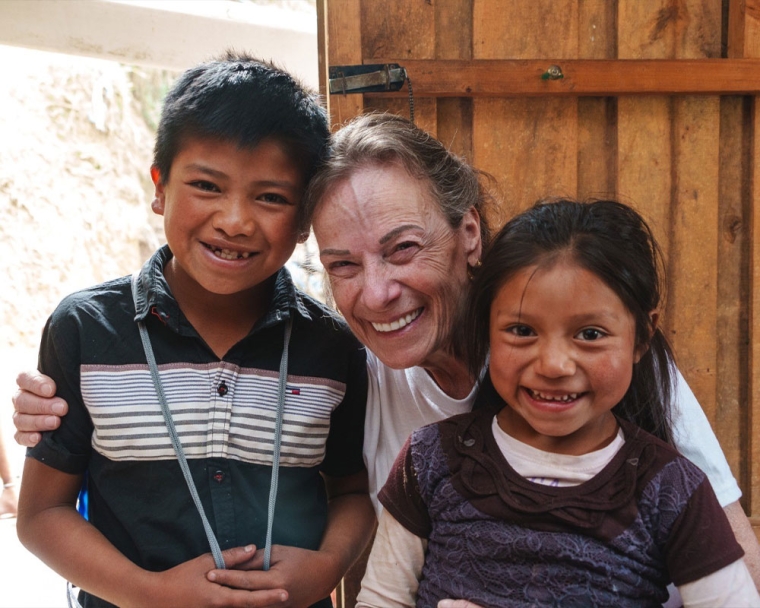 Karen Chambers smiling with two Smile Train patients after their cleft surgeries