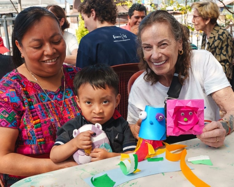Karen Chambers smiling with a cleft-affected patient and their mother after their surgery