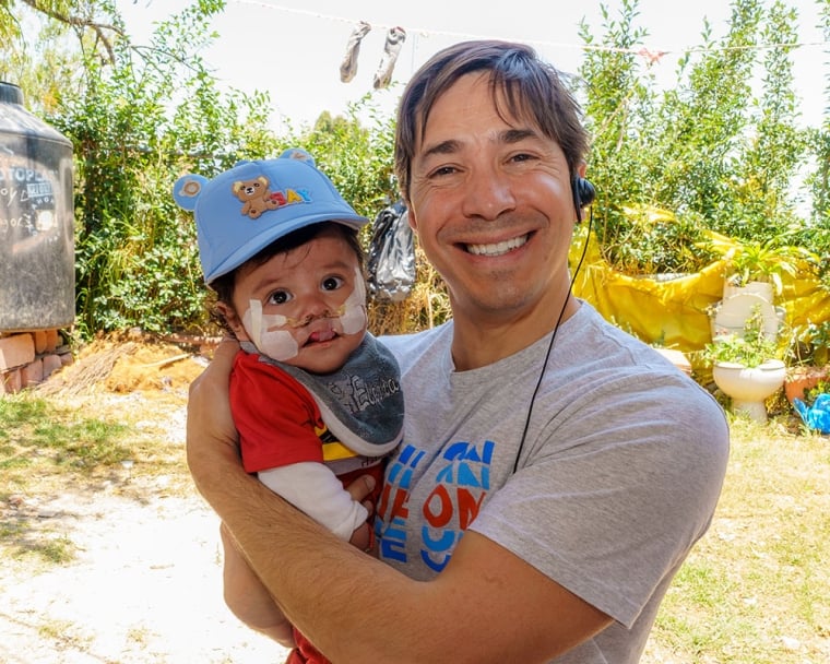 Justin Long smiling and holding an infant Smile Train patient in Mexico