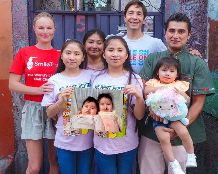 Justin Long and Kate Bosworth with Lizeth, Lizbeth, their baby sister, and their parents. The twins hold a picture of themselves as babies before cleft surgery