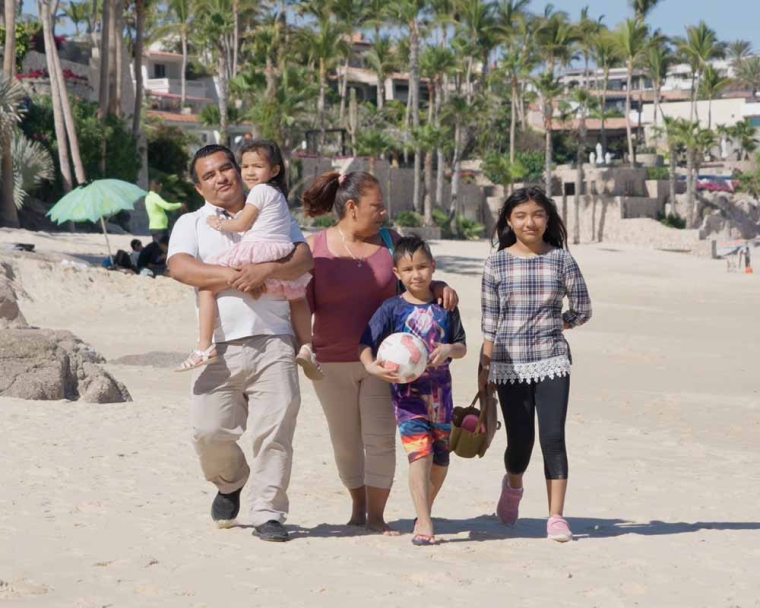 Adriana walks in the bright sun along the beach with her mother, father, little brother, and little sister
