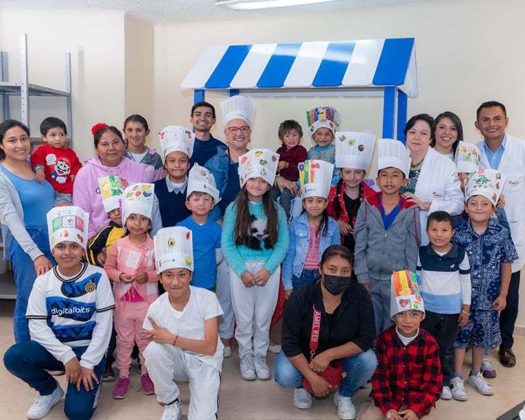Lidia posing with a group of Smile Train patients and their parents. All kids are wearing hand-decorated chef’s hats