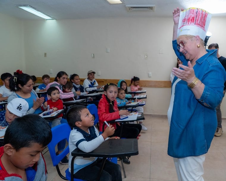 Lidia standing at the front of the room wearing a hand-decorated chef’s hat, addressing the kids