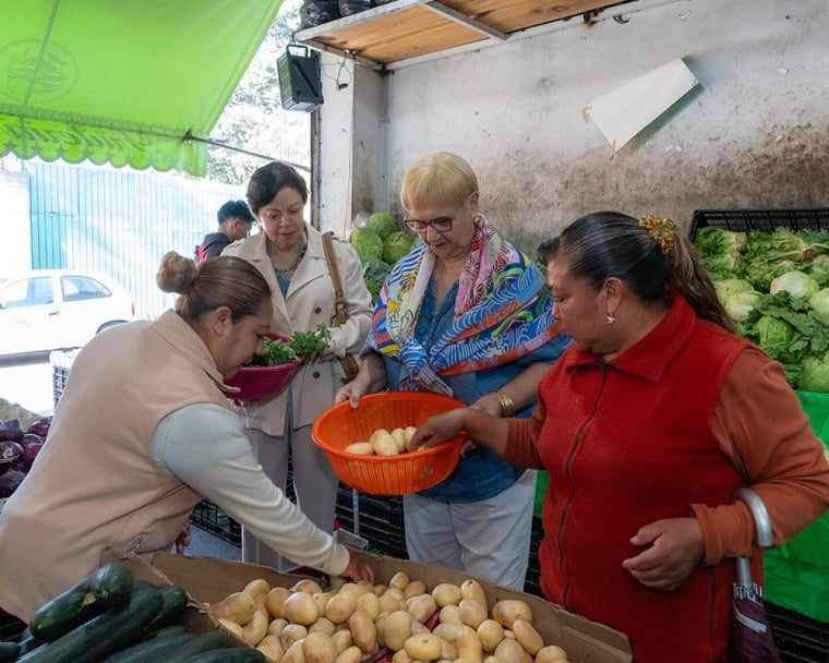 Lidia holding a basket of potatoes as another woman fills it up