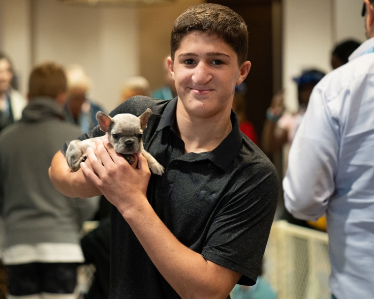 Chase Karenbauer holds a puppy with a cleft