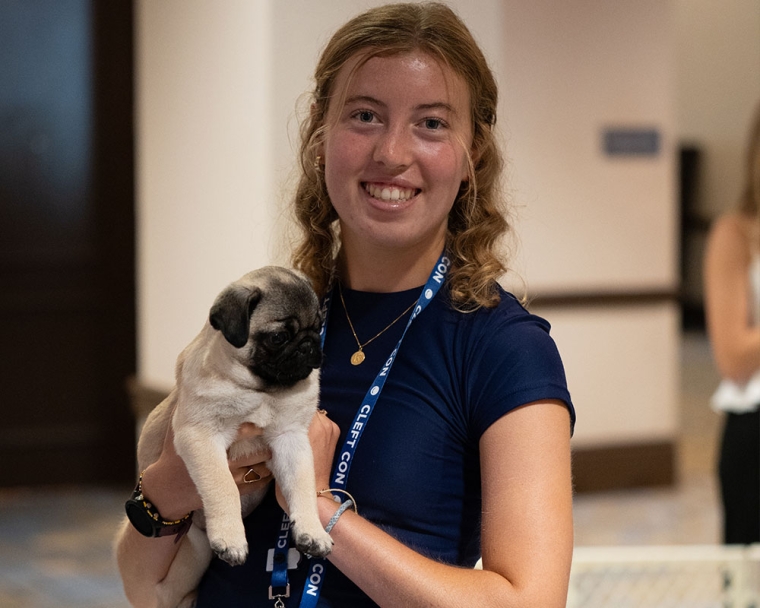 Cleft Con Orlando keynote speaker Campbell Hough holds a puppy with a cleft